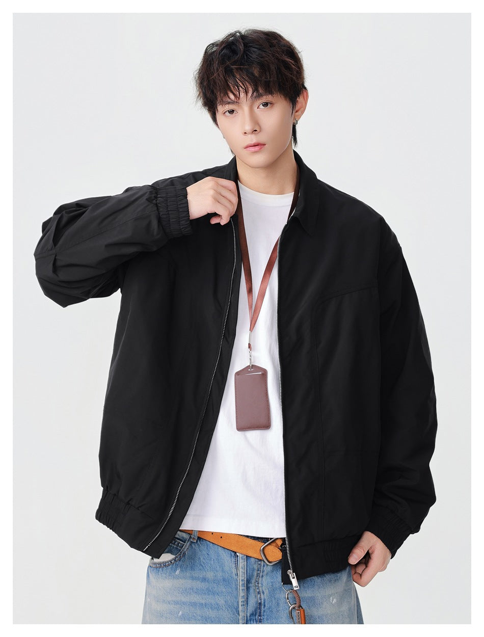 Front view of a model wearing a loose black collared jacket with a front zipper and elastic cuffs and hem.