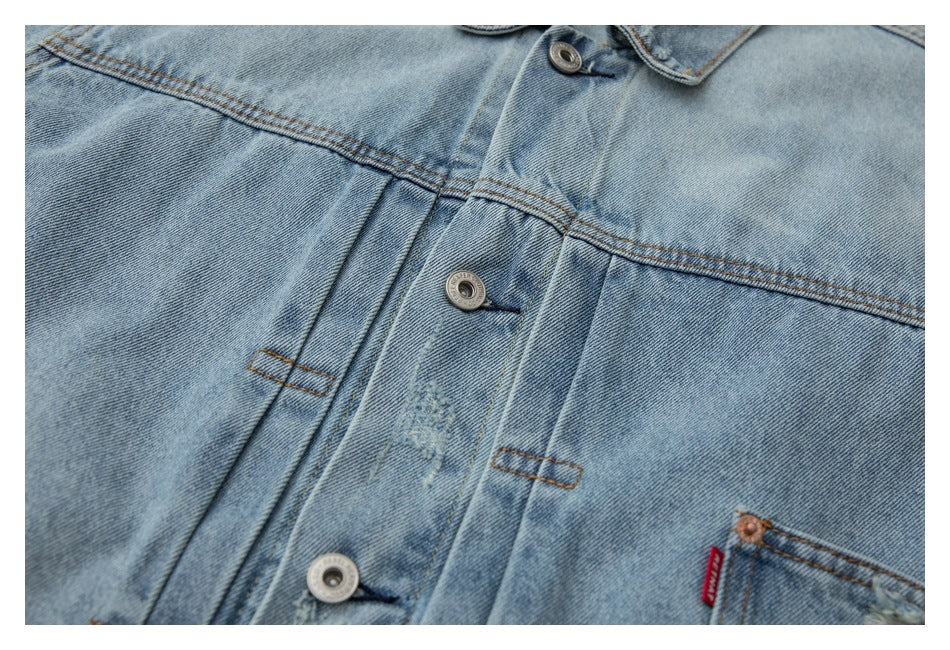 Close-up of a light blue denim jacket front placket, buttons, stitching, and chest pocket edge.