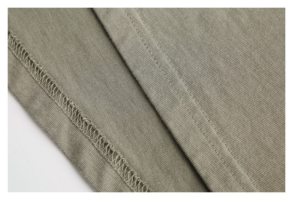 Close-up of a muted olive-gray garment showing parallel stitched seams and an overlock edge.