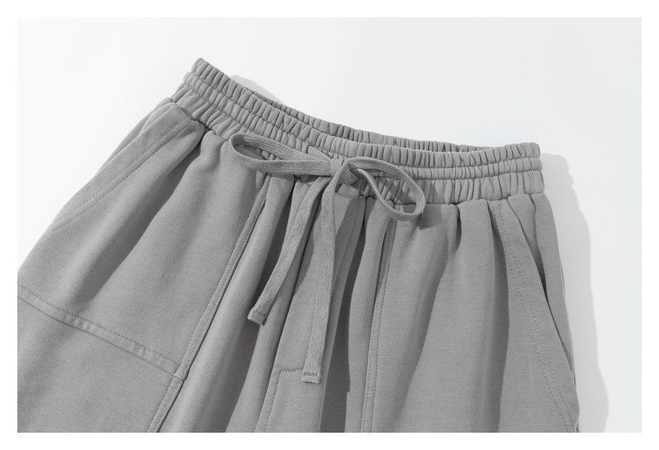 Close-up of light gray pants showing the elastic waistband, drawstring, and front pocket.