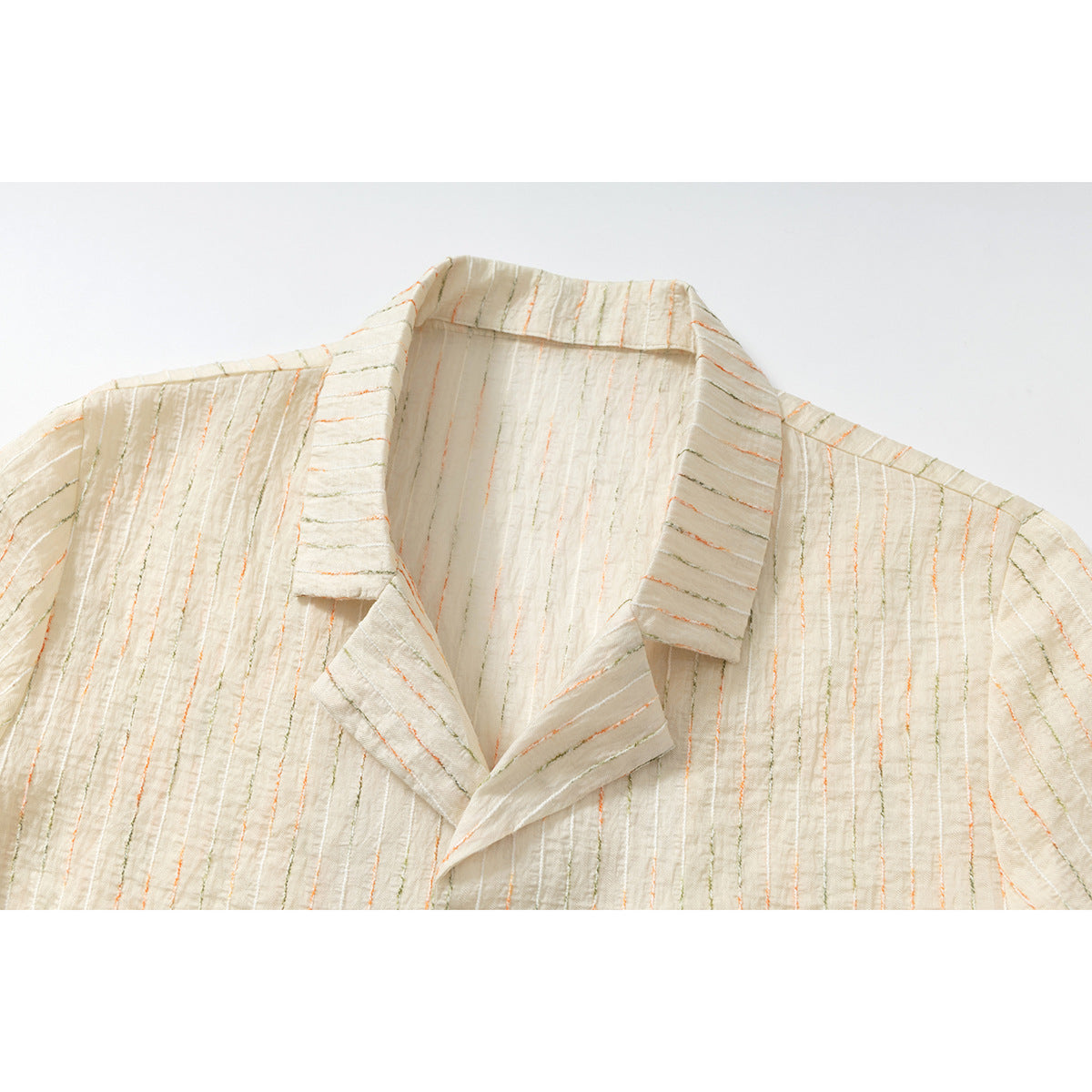 Close-up of an ivory short-sleeve shirt's notched collar and textured fabric with fine orange and olive stripes.