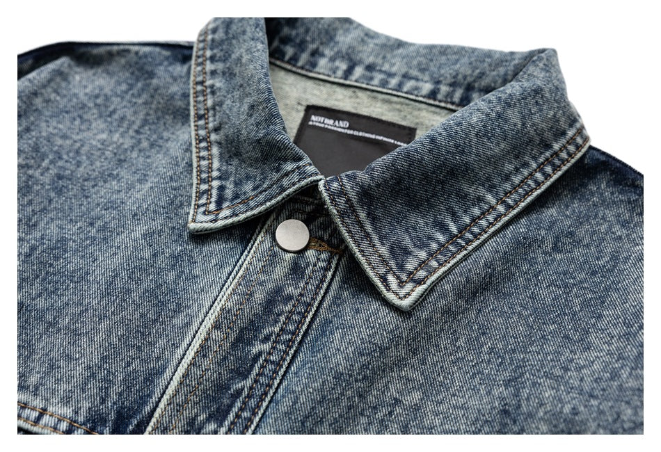 Close-up of a mottled blue denim jacket collar, metal snap and inner neck label.