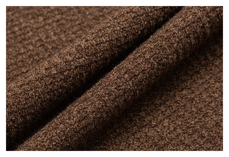 Macro view of brown knit fabric folded to show its thick textured stitch.