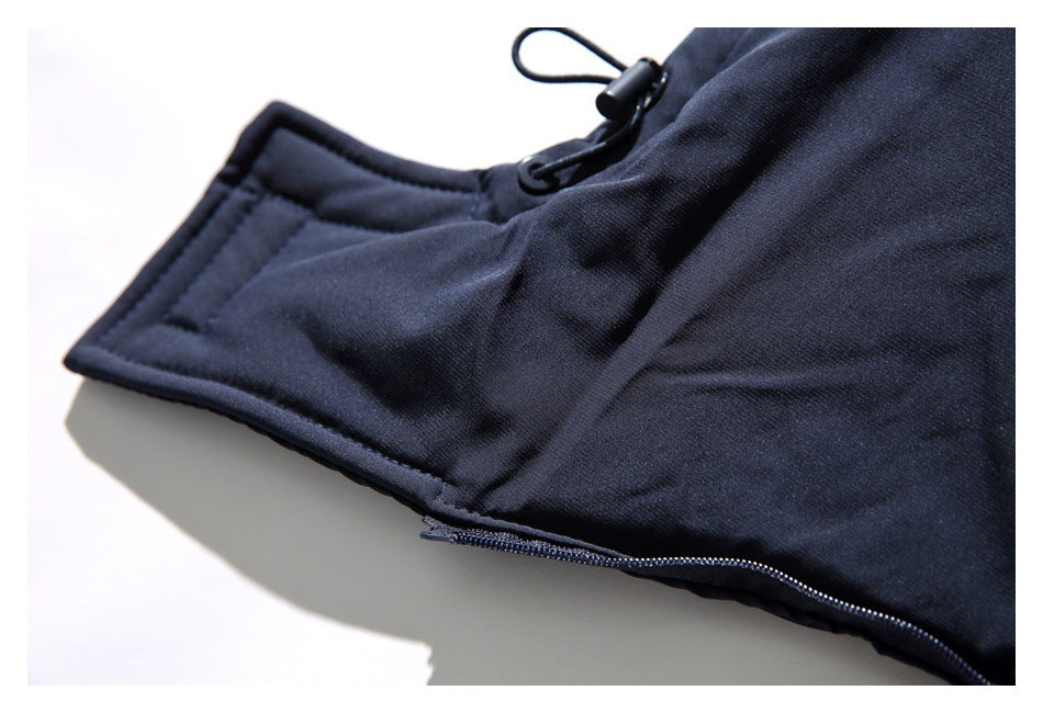 Close-up of the navy jacket's hood or collar edge, drawcord toggle, and zipper.