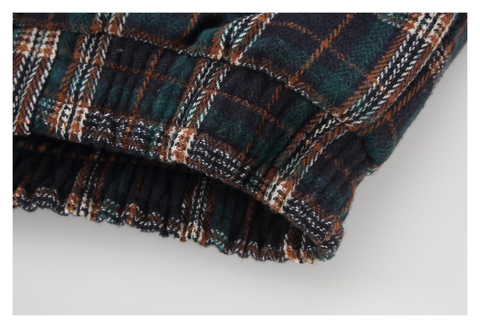 Close-up of a dark plaid garment edge with a gathered black section underneath.