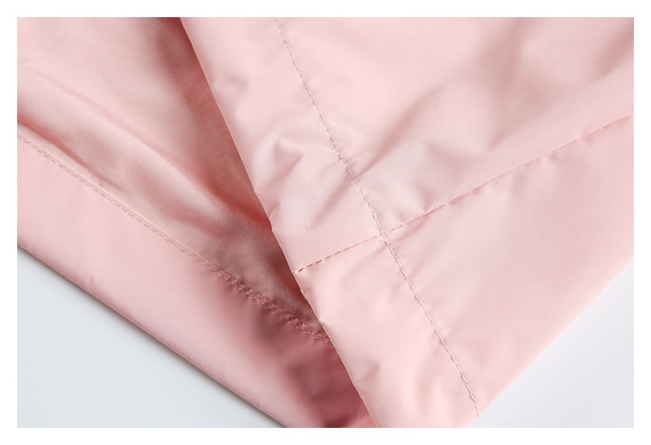 Close-up of overlapping pale pink garment fabric showing stitched seams and an edge finish.