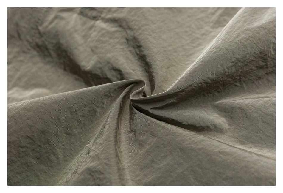 Extreme close-up showing the gray-green garment's wrinkled surface and fabric folds.