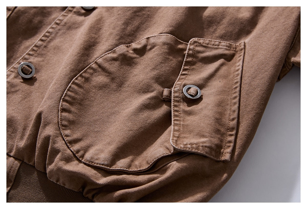 Close-up of a large flap pocket and dark ring-style button on a brown jacket.