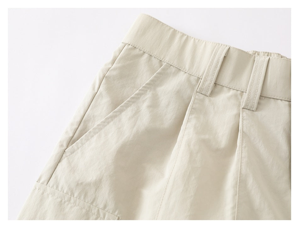 Close-up of cream trousers showing the waistband, belt loops, and angled front pocket.