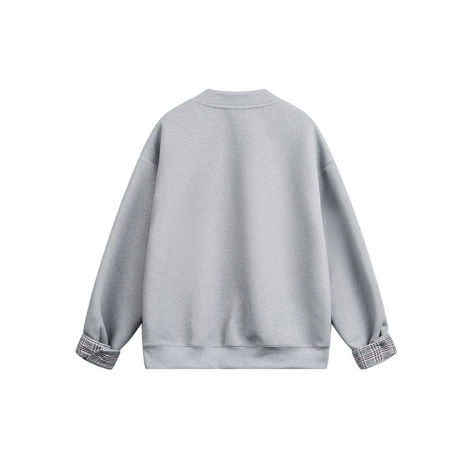 Back view of gray textured jacket with ribbed hem and plaid-lined cuffs, flat lay