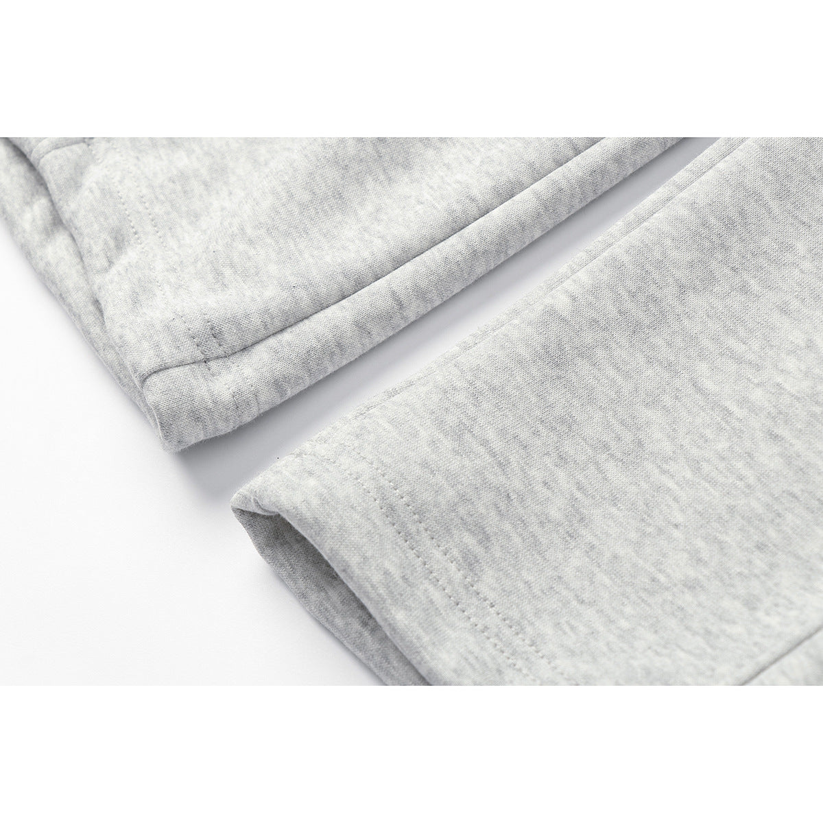 Close-up of the stitched hems of light gray heathered sweatpants.