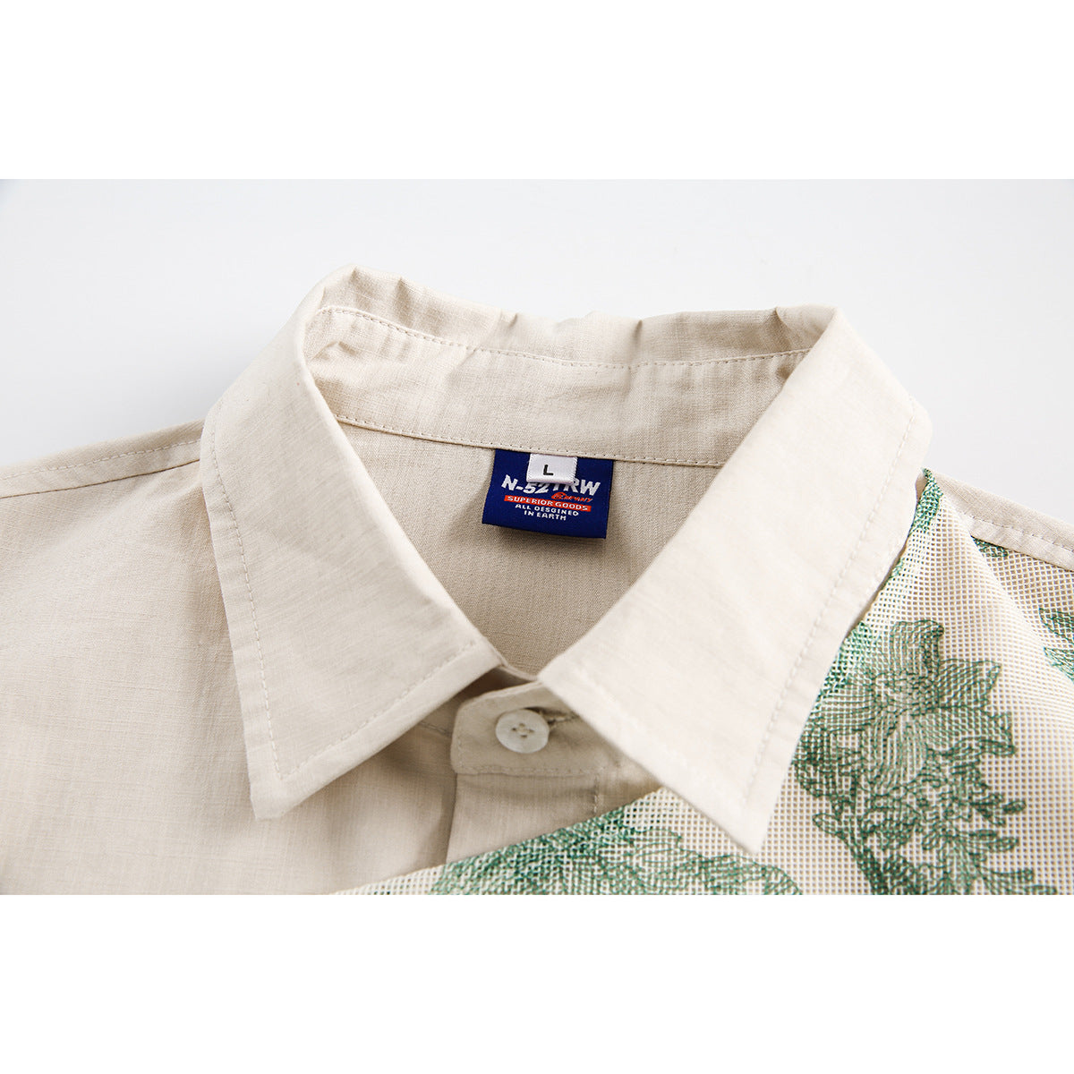 Close-up of a cream shirt collar, button, and neck label beside a green floral panel.