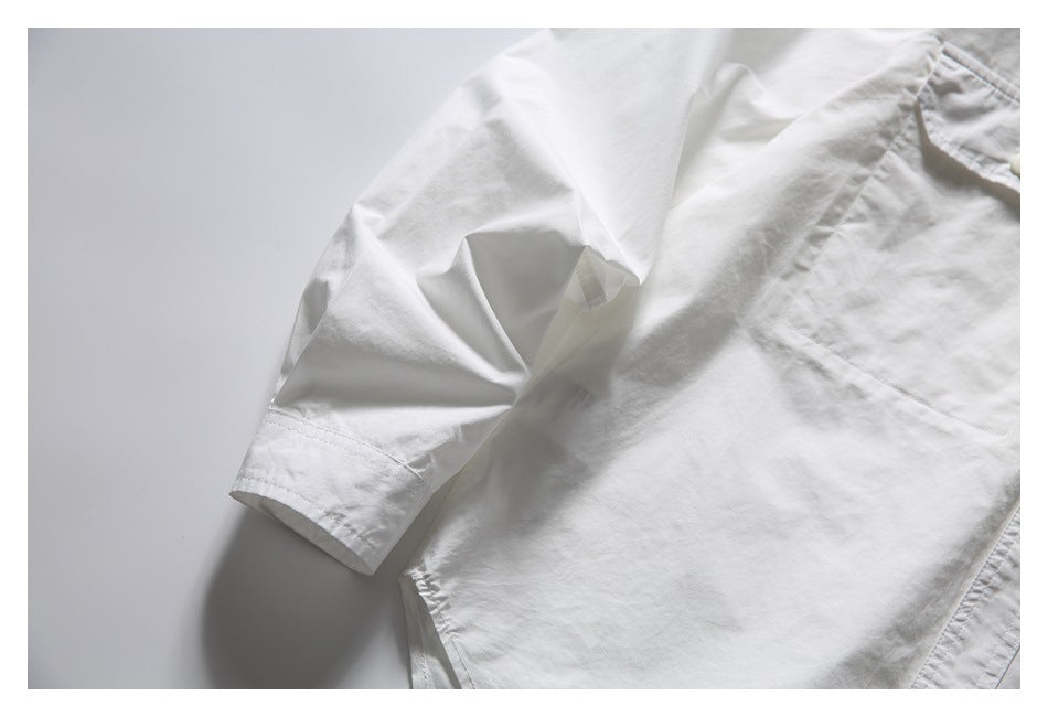 Close-up of the white shirt's long sleeve, cuff, and part of the front pocket.