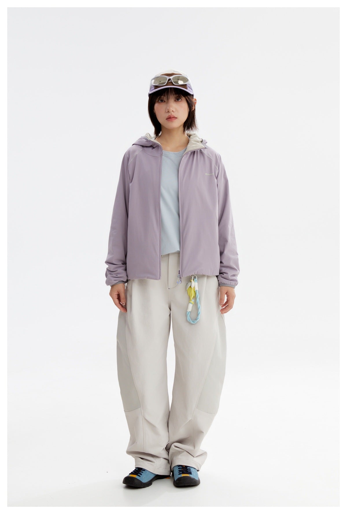 Model wearing a lavender hooded zip jacket and loose light trousers, shown from the front.