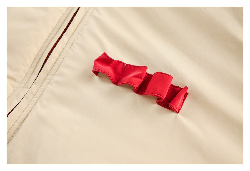 Close-up of a red fabric detail on the cream jacket beside the zipper seam.