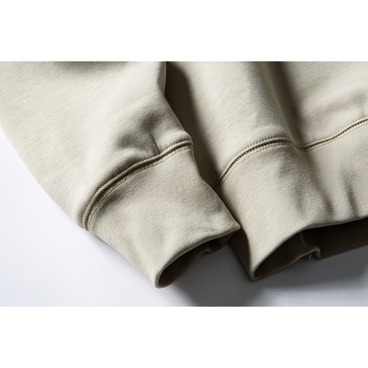 Close-up of the light beige sweatshirt's ribbed cuffs and stitched sleeve seams.