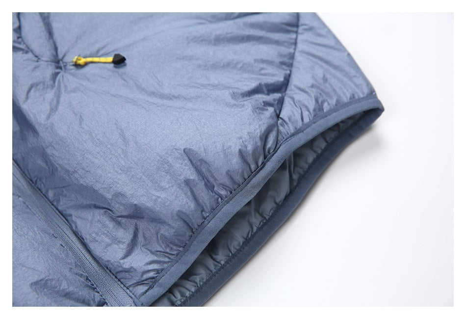 Close-up of a blue-gray garment edge with dark binding, inner lining, and a yellow cord toggle.