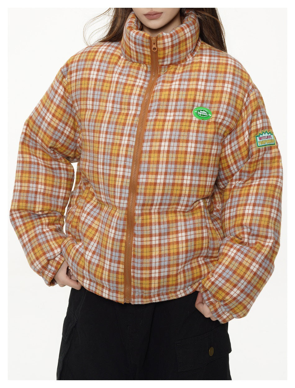 Close-up of the plaid puffer jacket showing its high collar, brown zipper, chest patch, and sleeve patch.