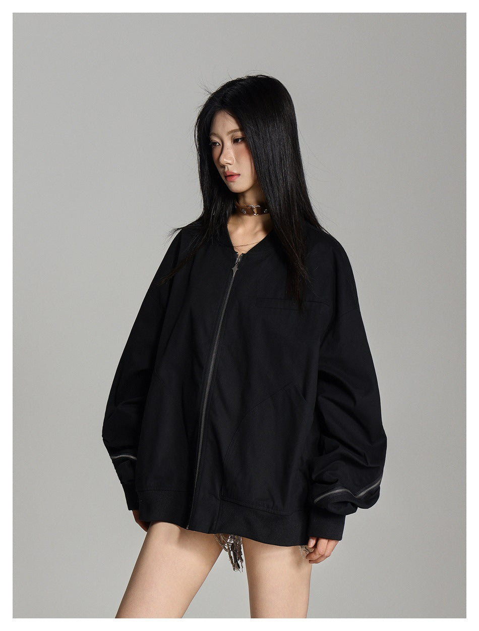 Model wearing an oversized black zip-front jacket with large sleeves, front pockets, and zipper details at the cuffs.