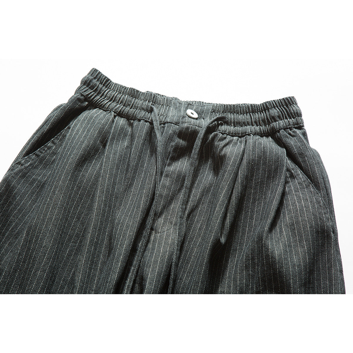 Close-up of dark gray pinstriped trousers showing the elastic waistband, button, drawstring and front pockets.
