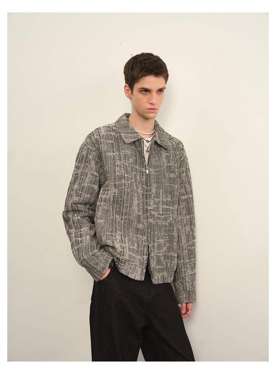 Three-quarter view of a model wearing a gray abstract-patterned zip-front jacket with black pants.