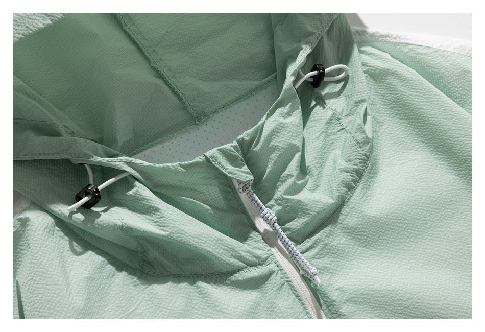 Close-up of a pale mint jacket hood showing the inner panels, white drawcords, toggles and zipper.