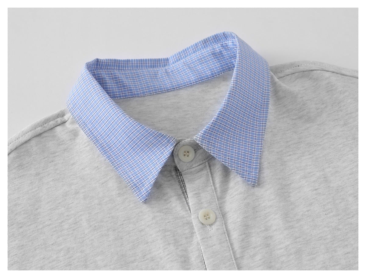 Close-up of a light gray shirt with a blue plaid pointed collar and two pale buttons.