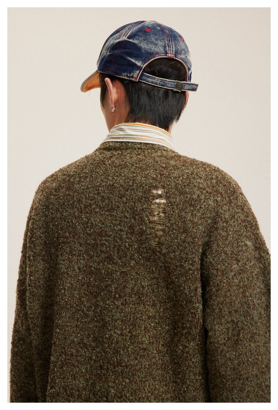 Close-up rear view of an olive-brown textured sweater, showing a distressed opening near the upper back.