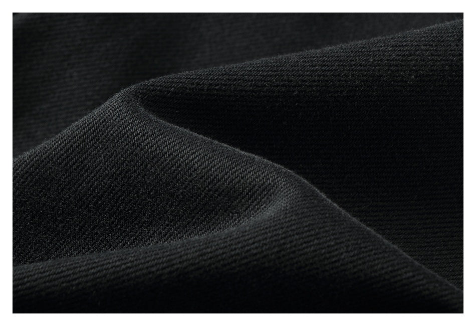 Close-up of black fabric showing its fine textured weave and folded edge.