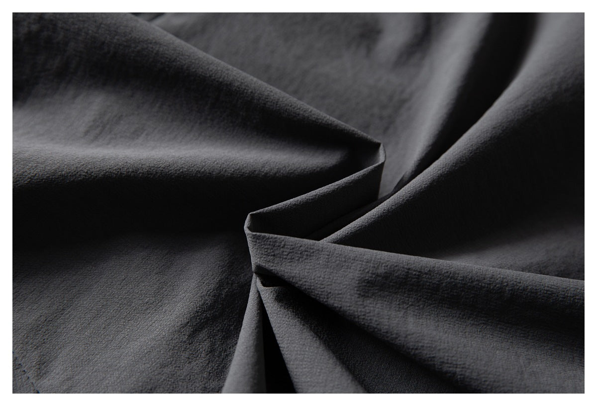 Close-up of dark charcoal fabric in folds, showing a smoother, subtly textured surface.