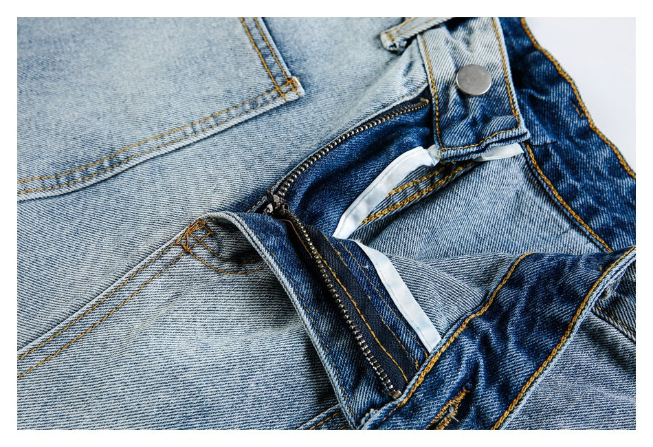 Close-up of light-wash jeans with the metal zipper fly open and waistband button visible.
