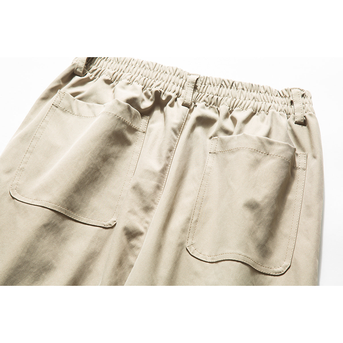 Close-up of the beige trousers' back waistband and two large patch pockets.