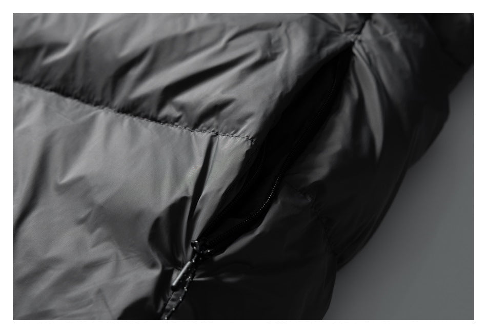Close-up of an open black pocket zipper against the dark gray quilted jacket.