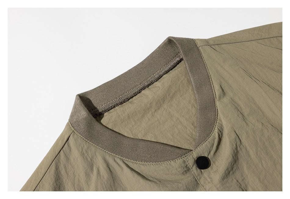 Close-up of an olive-taupe garment neckline with ribbed trim and a black snap button.