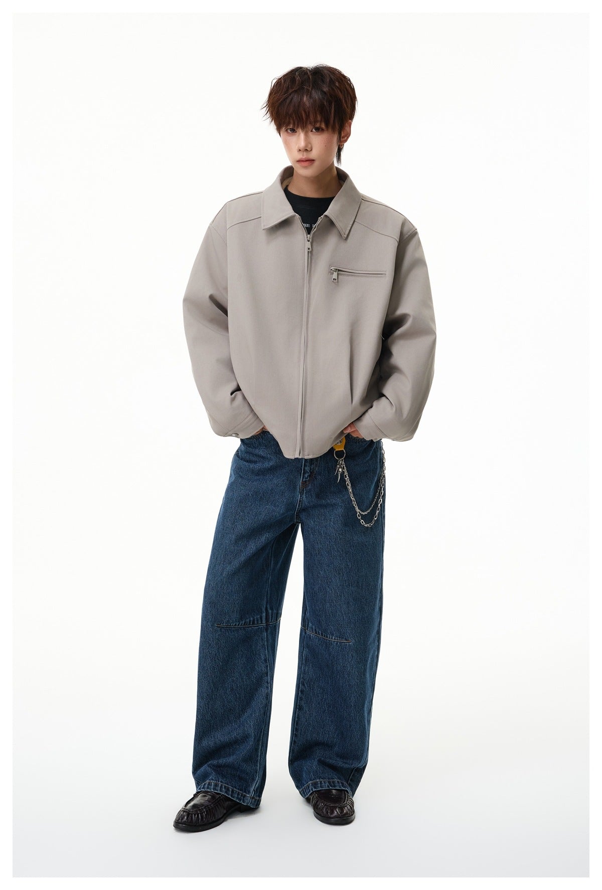 Full-length view of a model wearing a light taupe zip jacket with a chest pocket and wide blue jeans.