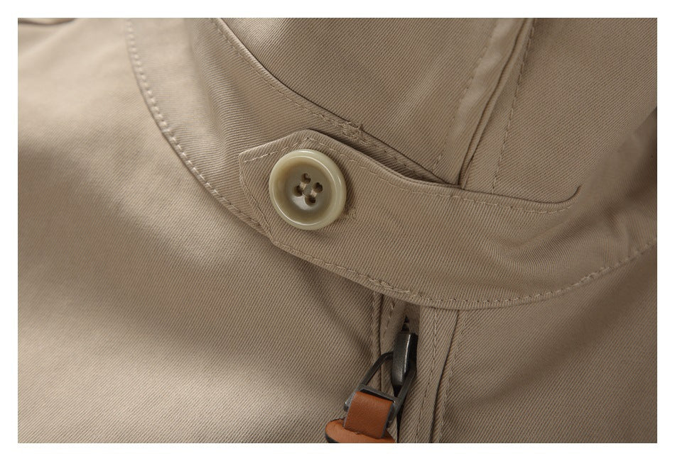 Close-up of a beige jacket's collar tab and button beside the zipper pull.
