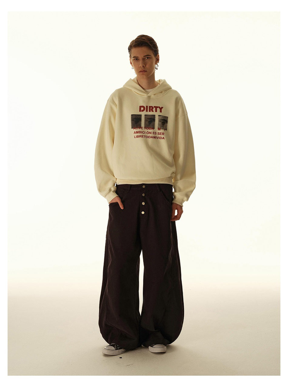 Model wearing a cream graphic hoodie and very wide black trousers, shown full length against a light studio backdrop.