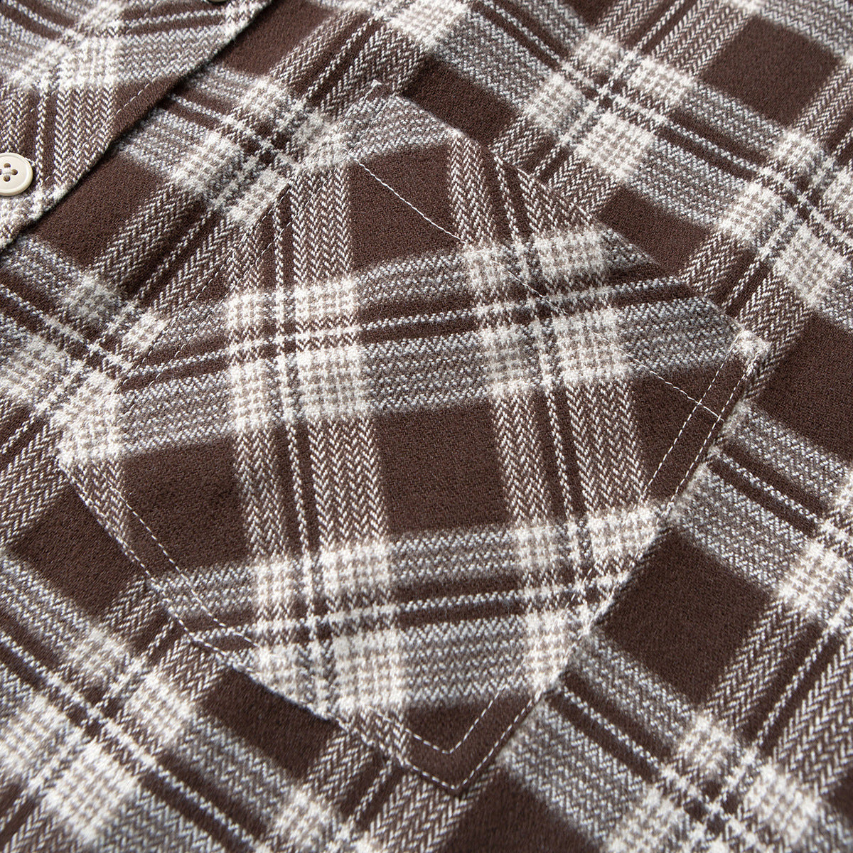 Close-up of a brown and cream plaid shirt's stitched chest pocket and fabric pattern.