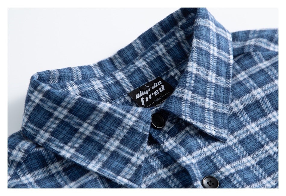 Close-up of a blue-and-white plaid shirt collar with black buttons and a sewn-in neck label.