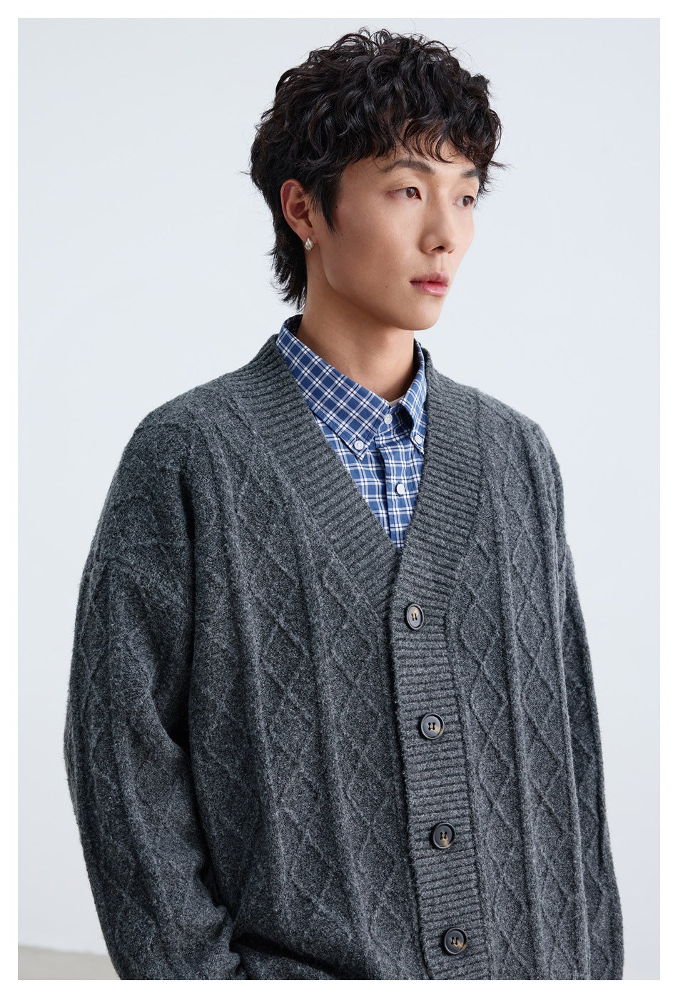 Close view of a dark charcoal cable-knit cardigan with ribbed V-neck trim and dark buttons.
