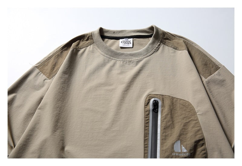 Close-up of the pullover's chest pocket with a vertical zipper, shoulder panels and small garment logo.