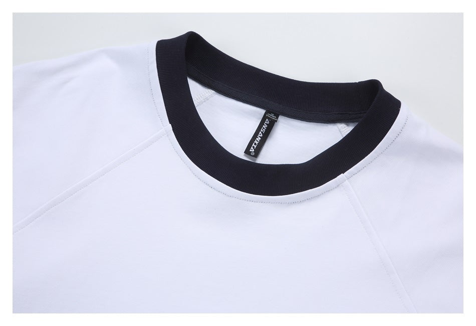Close-up of a white shirt with a black ribbed crew neckline and a small black neck label.