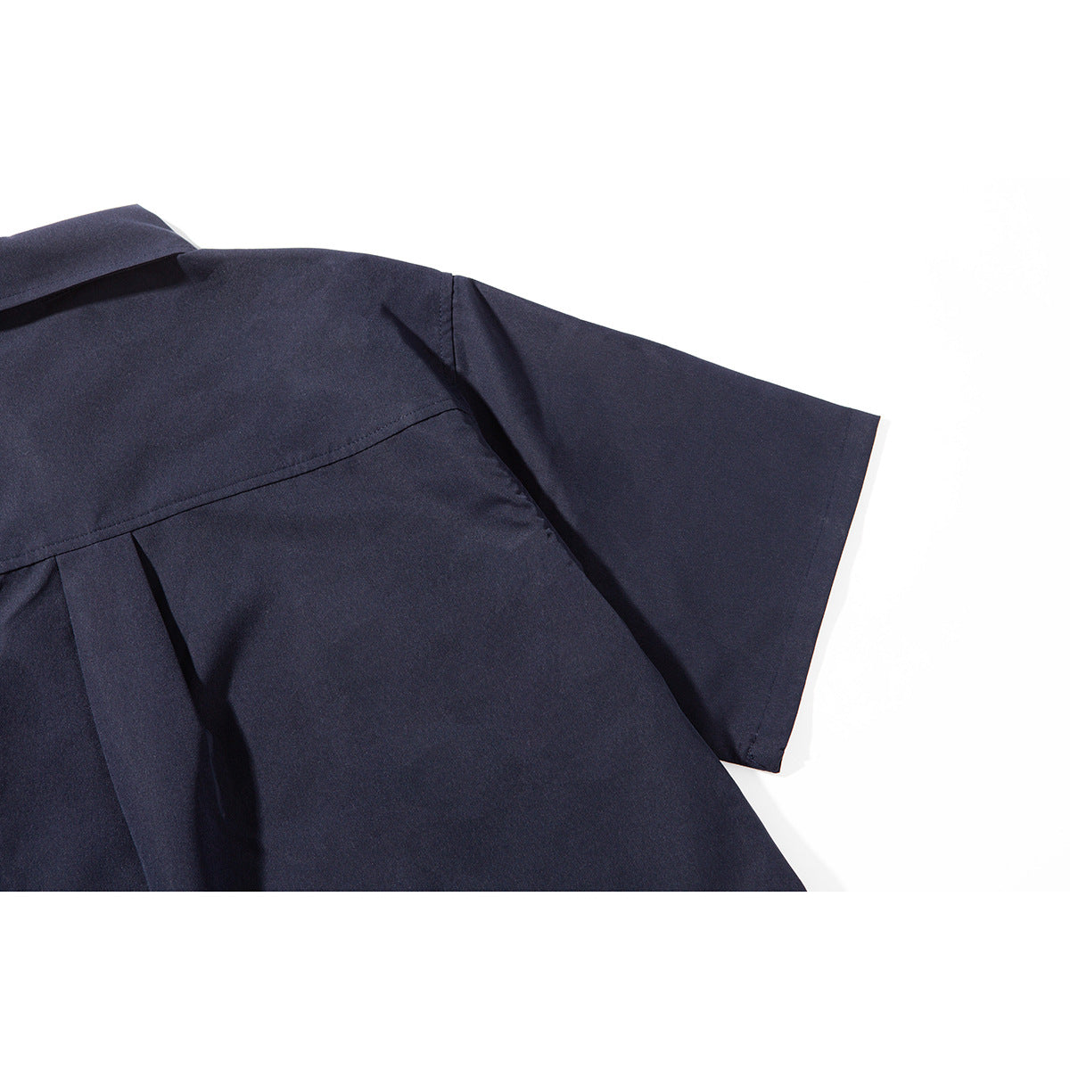 Close-up of the dark navy shirt's back yoke, center pleat, and short sleeve.