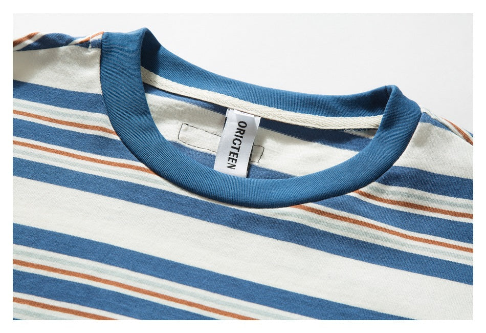 Close-up of a striped T-shirt's blue crew neck and cream, blue, rust, and pale green pattern.