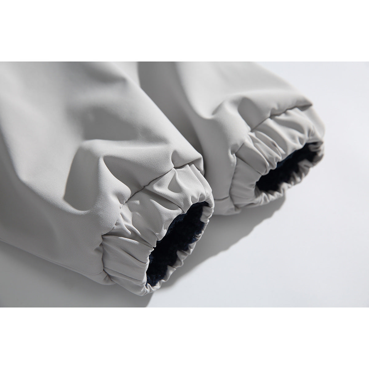 Close-up of two light gray jacket sleeve cuffs, gathered with elastic and lined in dark fleece.