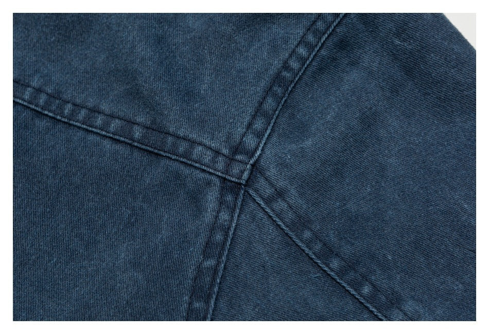 Close-up of intersecting stitched seams on dark blue denim.