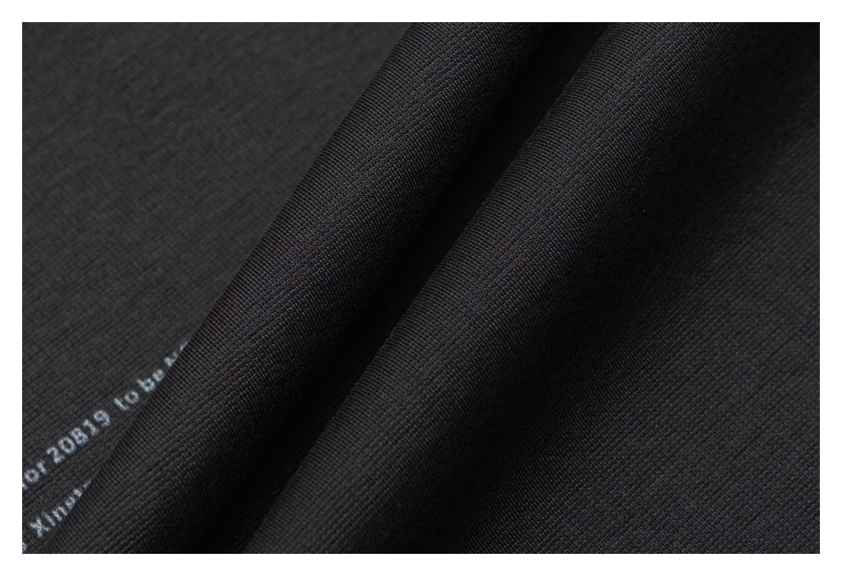Macro view of dark garment fabric folded into ridges, with a small portion of printed English lettering visible.