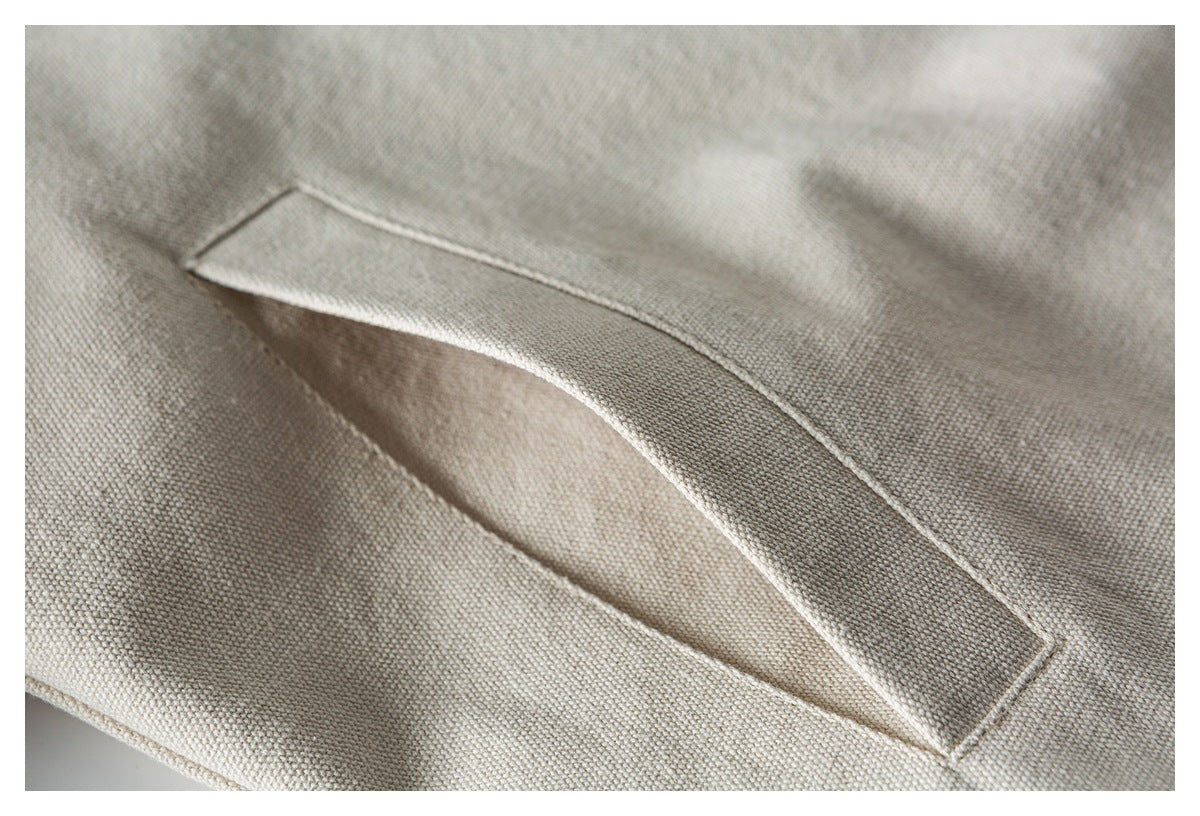 Close-up of a light beige woven textile with a stitched narrow pocket opening.