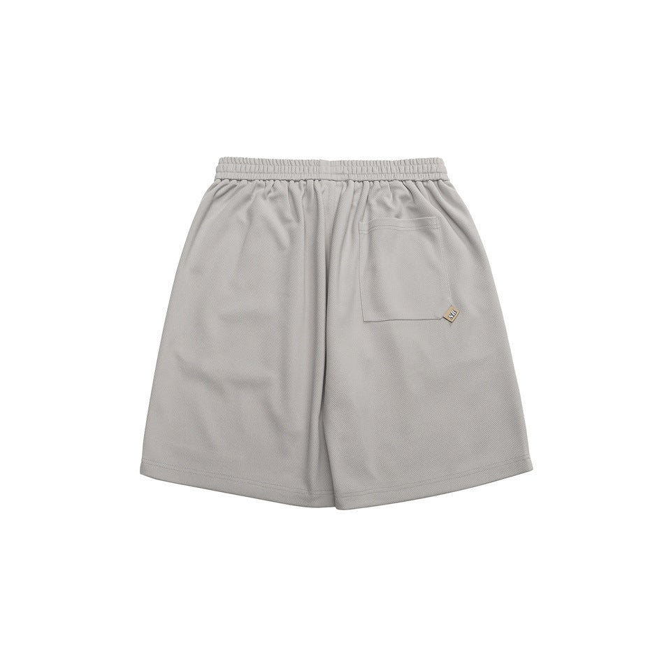 Back view of gray shorts with elastic waistband and a patch pocket with a small tan label