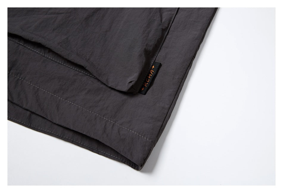 Close-up of the dark charcoal garment hem and a small sewn-on label.